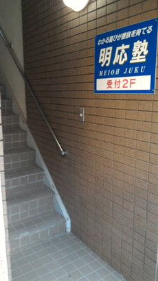 明応塾2fへ至る階段と壁に表示された看板